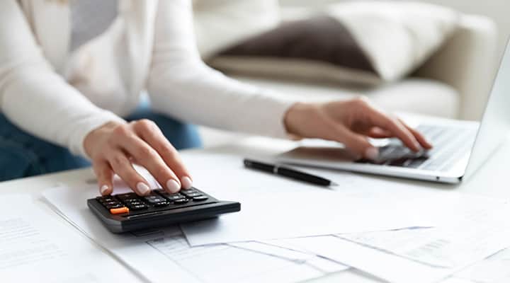 view of woman's arms using a calculator and laptop to calculate business storage taxes
